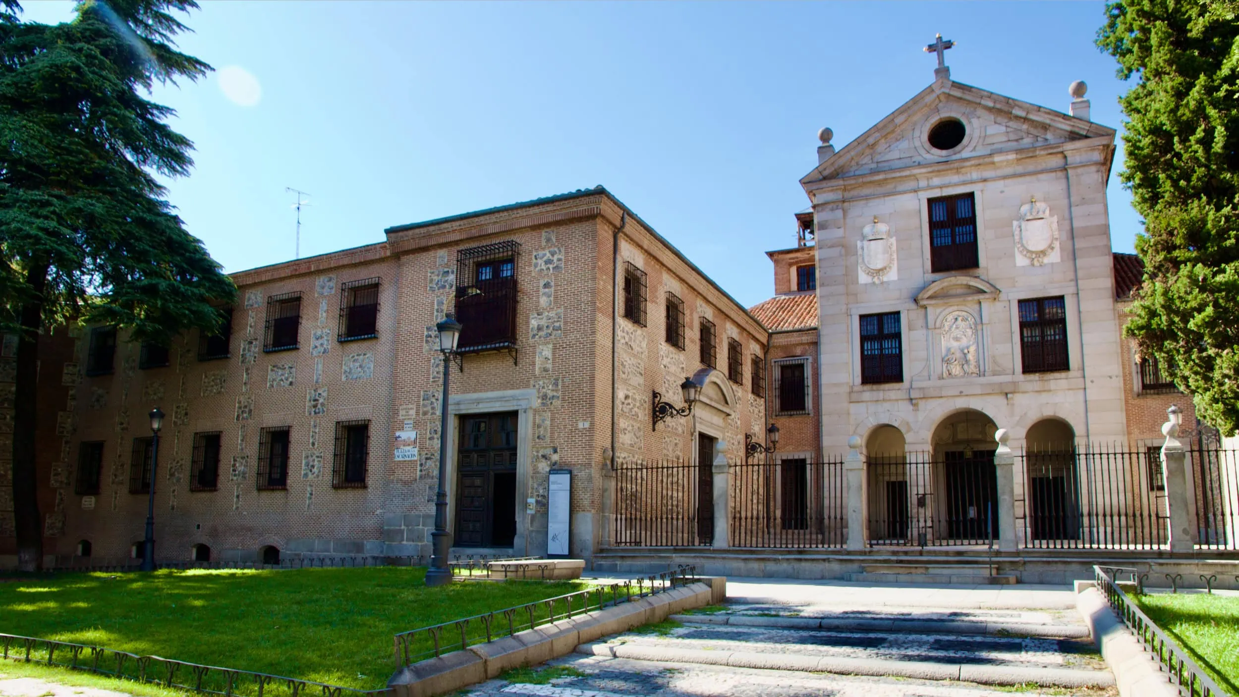 Voorzijde van het Monasterio de la Encarnación in Madrid met voortuin, patio in Herrerastijl en bomen die het zeventiende-eeuwse karakter van het complex benadrukken.