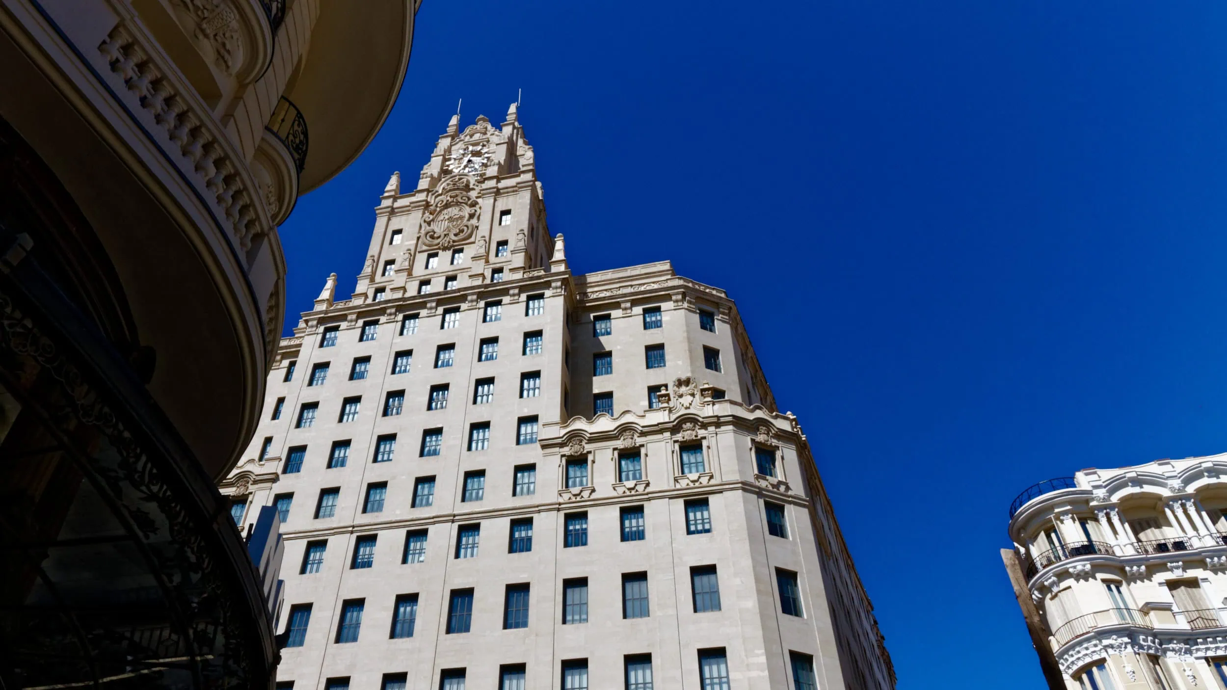 Het Edificio Telefónica aan de Gran Vía in Madrid, ooit het hoogste gebouw van Europa, met monumentale neobarokke architectuur tegen een intens blauwe lucht.