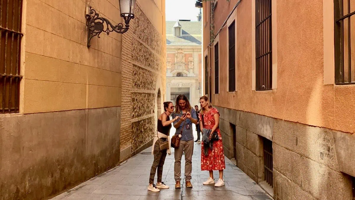 Privégids met twee gasten in Calle del Codo nabij Plaza de la Villa, een van de smalste straatjes van het oude Madrid, terwijl de route wordt toegelicht.