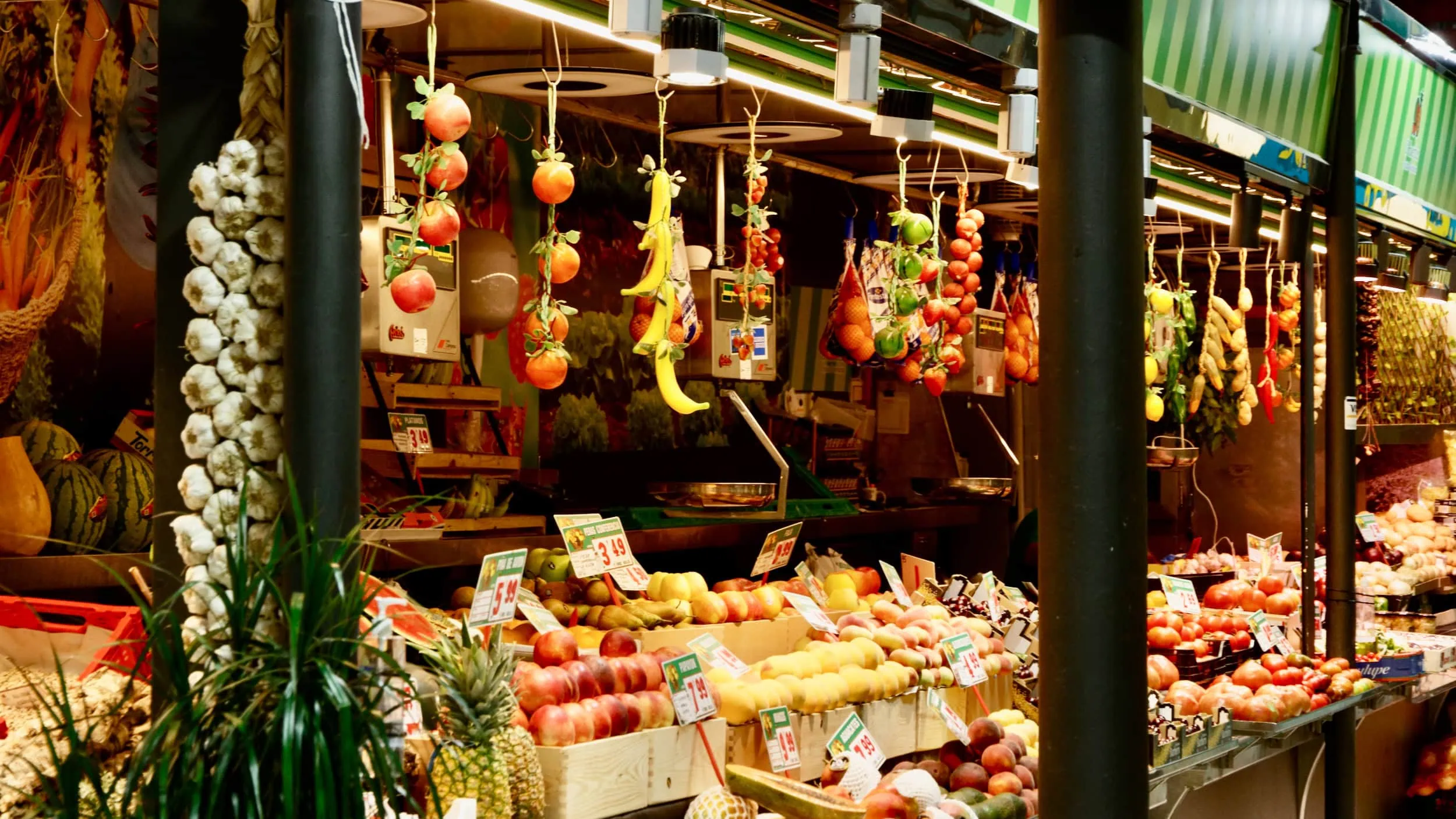 Kleurrijke fruit- en groentestand op een lokale markt in Madrid met onder meer knoflook uit Chinchón, appels, tomaten en tropisch fruit.